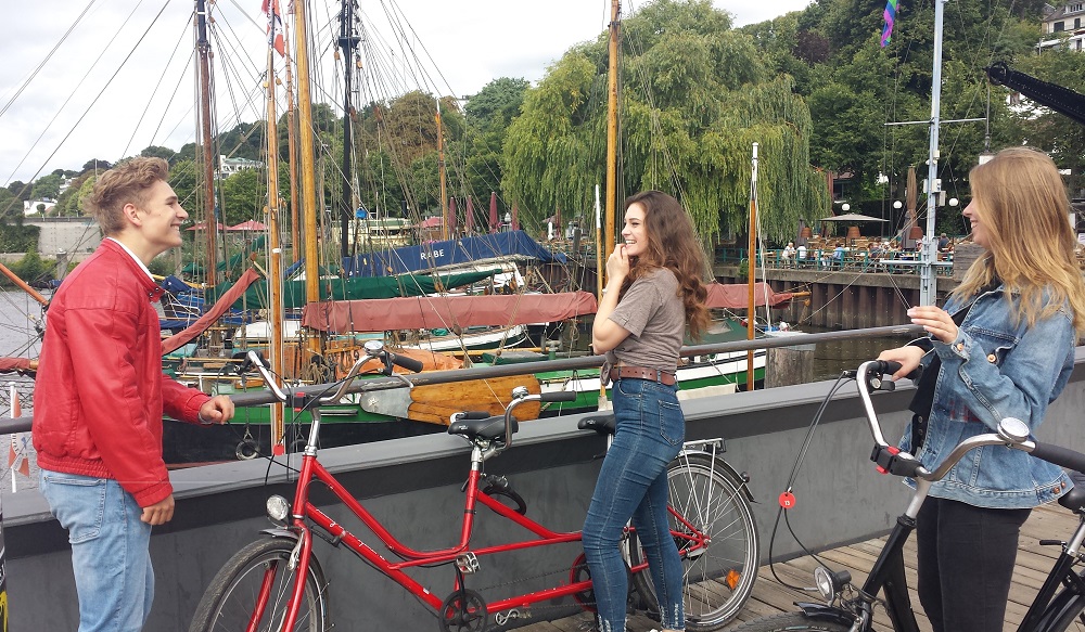 Junge Leute mit rotem Verleih Tandem vor dem Museumshafen