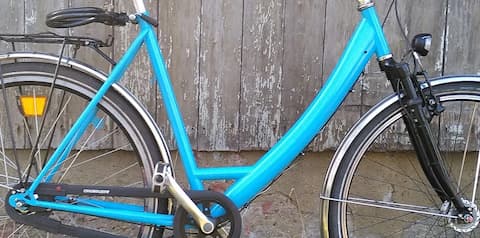 Hellblaues City Bike mit Nabenschaltung und Rücktrittbremse vor grauer Holzwand