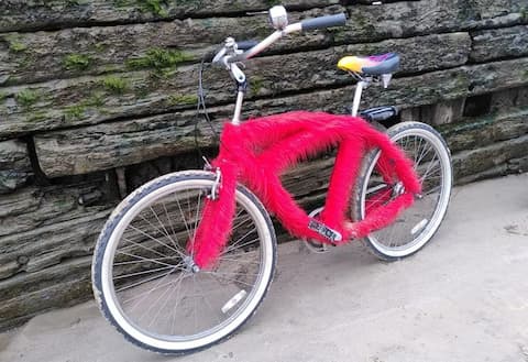 Beach Cruiser mit rotem Fell vor vermooster Schiffswand am Blankeneser Ufer