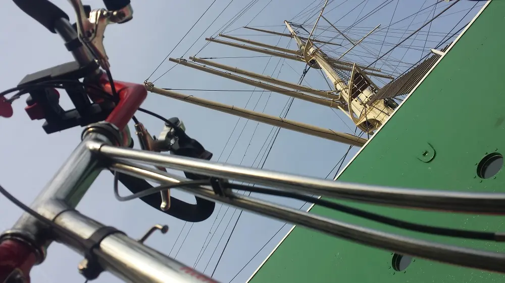 Blankes Edelstahl Fahrrad vor grünem Segelschiff