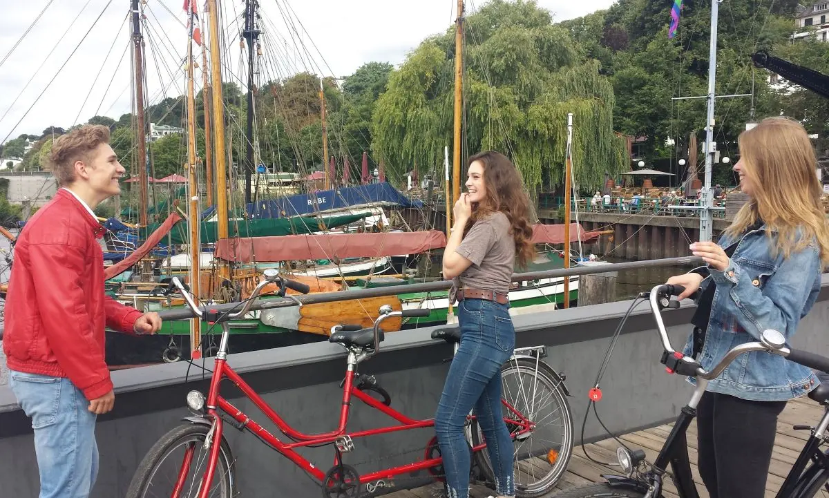 Junge Leute mit rotem Verleih Tandem vor dem Museumshafen